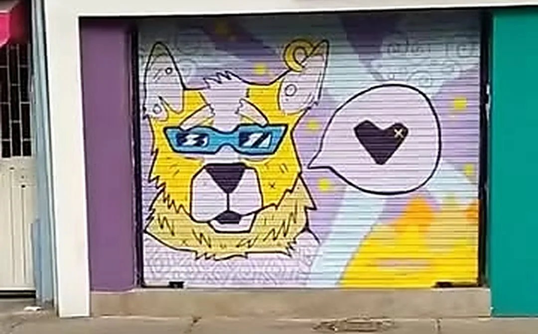 La reja de Manuelita Pets pintada con un mural de un perro amarillo y peludo con gafas de sol azules, junto a un bocadillo con un corazón, sobre lavanda, violeta y amarillo